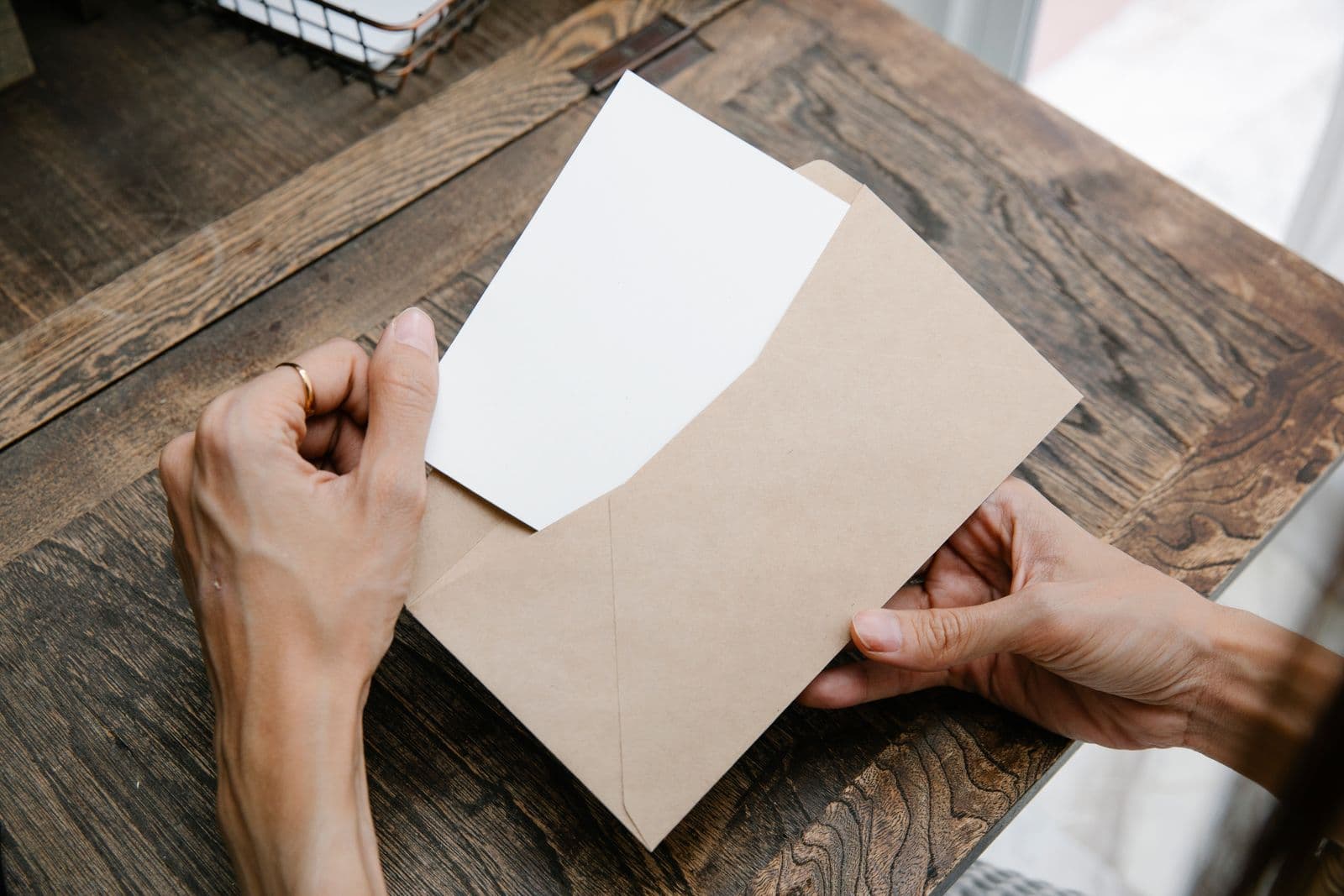 Une lettre sortie de son enveloppe kraft, posée sur un bureau en bois