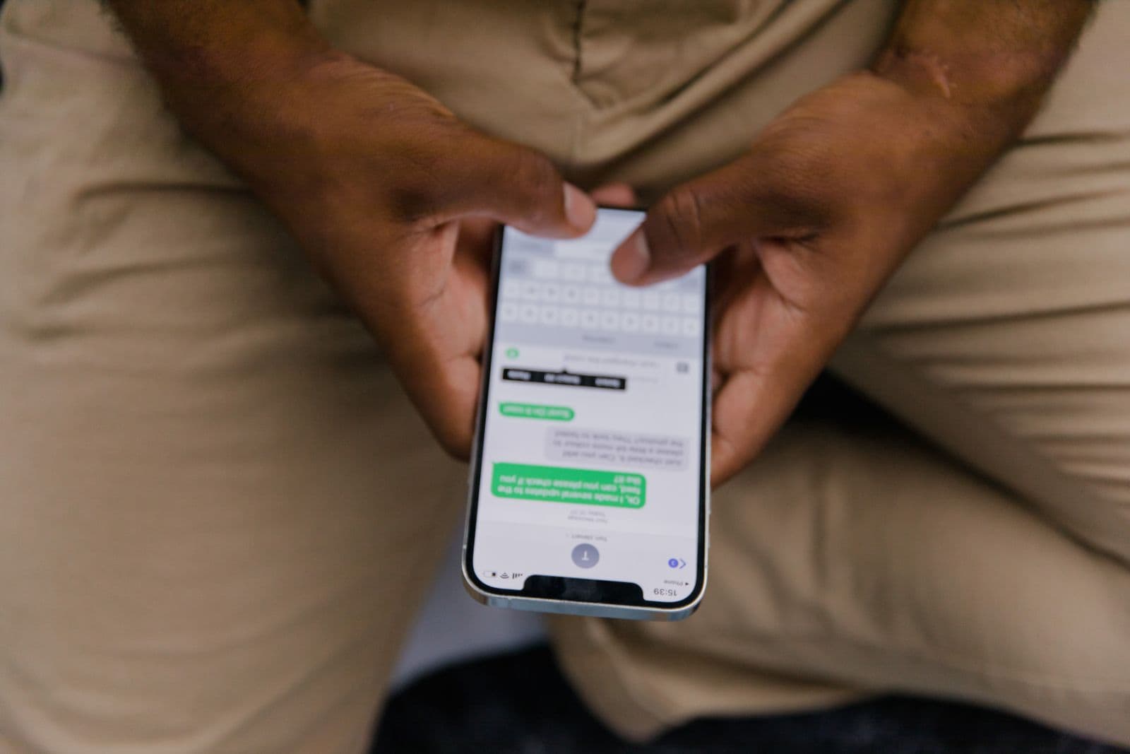 Des mains tenant un téléphone avec une conversation par messages à l'écran