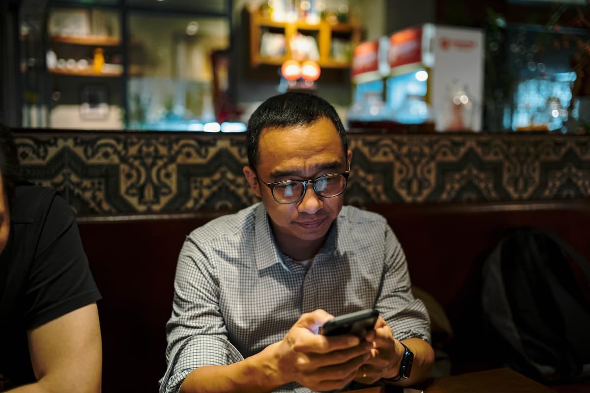 Restaurateur consultant une notification sur son téléphone dans la salle de son restaurant