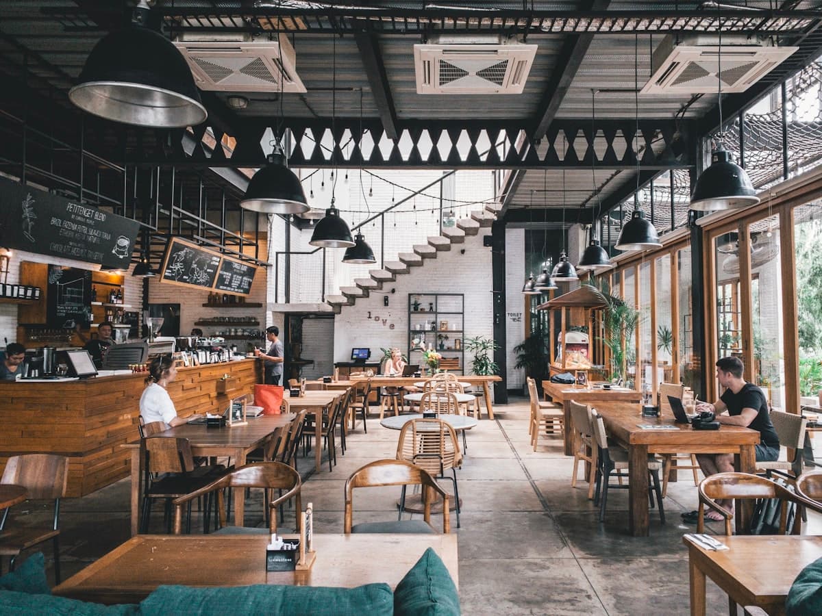 Salle de restaurant chaleureuse avec tables en bois et clients attablés