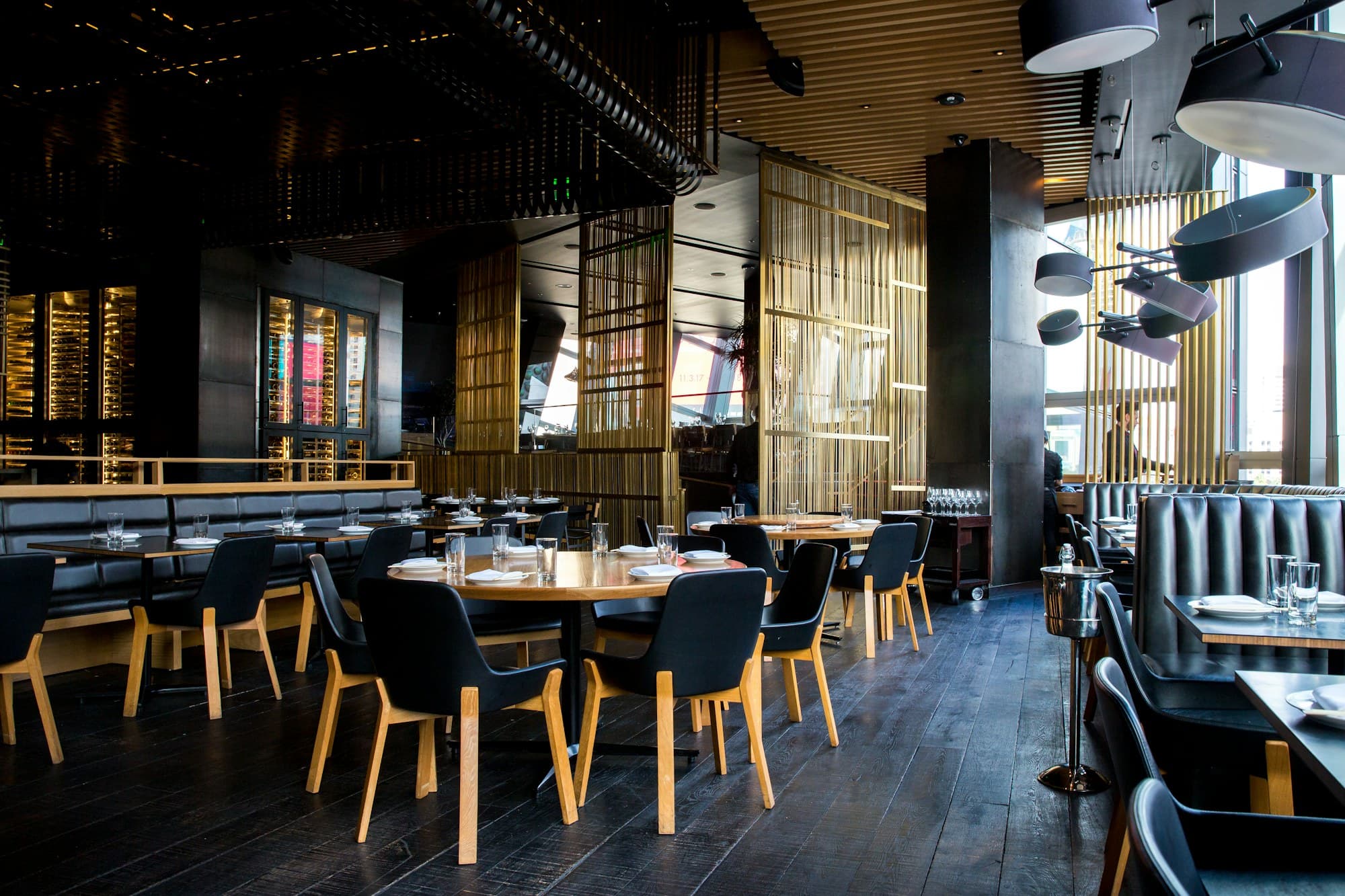 Salle d'une brasserie française à la lumière chaude du soir, tables dressées prêtes pour le service