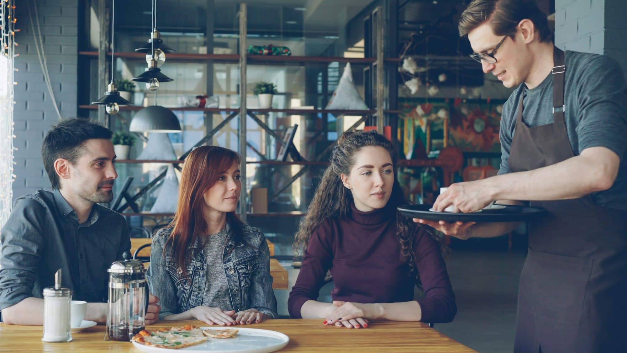 Serveur apportant un plat à des clients attablés dans un restaurant